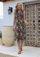 Woman is wearing a midi length retro floral print dress with button through front, pockets and a collar.