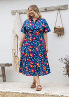 Woman wearing 100 percent cotton button through shirt dress with collar and short sleeves, in a royal blue based floral print. 