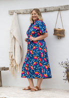 Model stands wearing a shirt style button through cotton dress with collar and a removable waist tie.