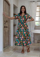 Model standing wearing a floral printed shirt dress with detachable fabric belt and short sleeves 
