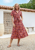 Woman wears 100% cotton warm toned button through shirt style dress with pockets, collar, short sleeves and a fabric waist tie.