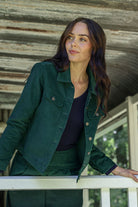 Woman in a corduroy jacket standing on a porch with a rustic background