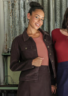 Woman wearing a brown cotton corduroy jacket over a dusky pink top and a brown corduroy skirt
