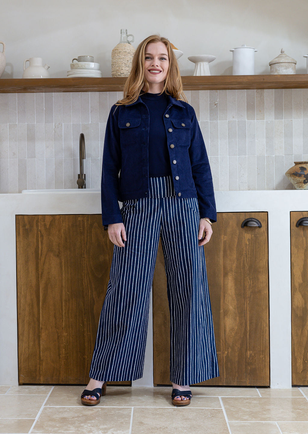 Woman wearing a deep, rich, and slightly muted navy blue long sleeve jacket with front and breast pockets