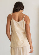 Back view of woman wearing lightweight cotton cami in nude tone, with adjustable spaghetti straps and a picot trim, paired with matching cotton slip skirt