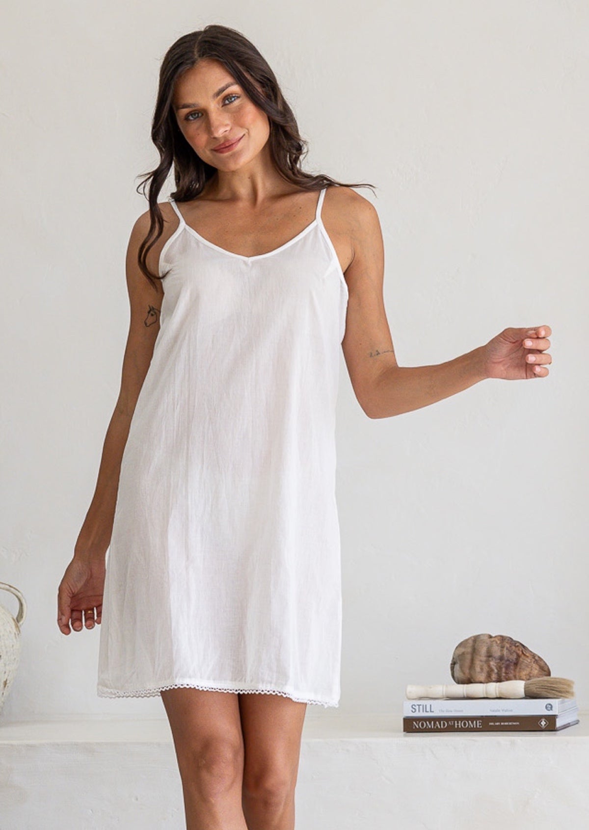 White cotton slip undergarment with thin straps and lace hem, above knee length