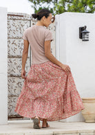 Model standing backwards wearing a three tiered, cotton maxi skirt with plain basic top