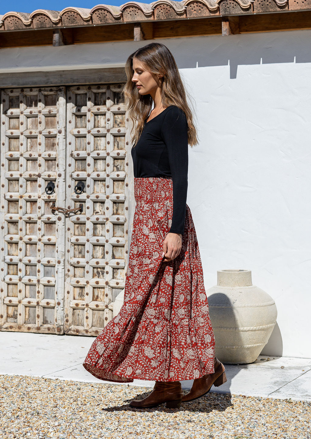 Model standing sideways wearing a three tiered, cotton maxi skirt with plain basic top