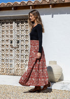 Model standing sideways wearing a three tiered, cotton maxi skirt with plain basic top