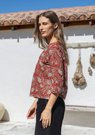 Woman stands sideways wearing relaxed fit, 100% cotton top in with loose 3/4 sleeves and wide round neckline.