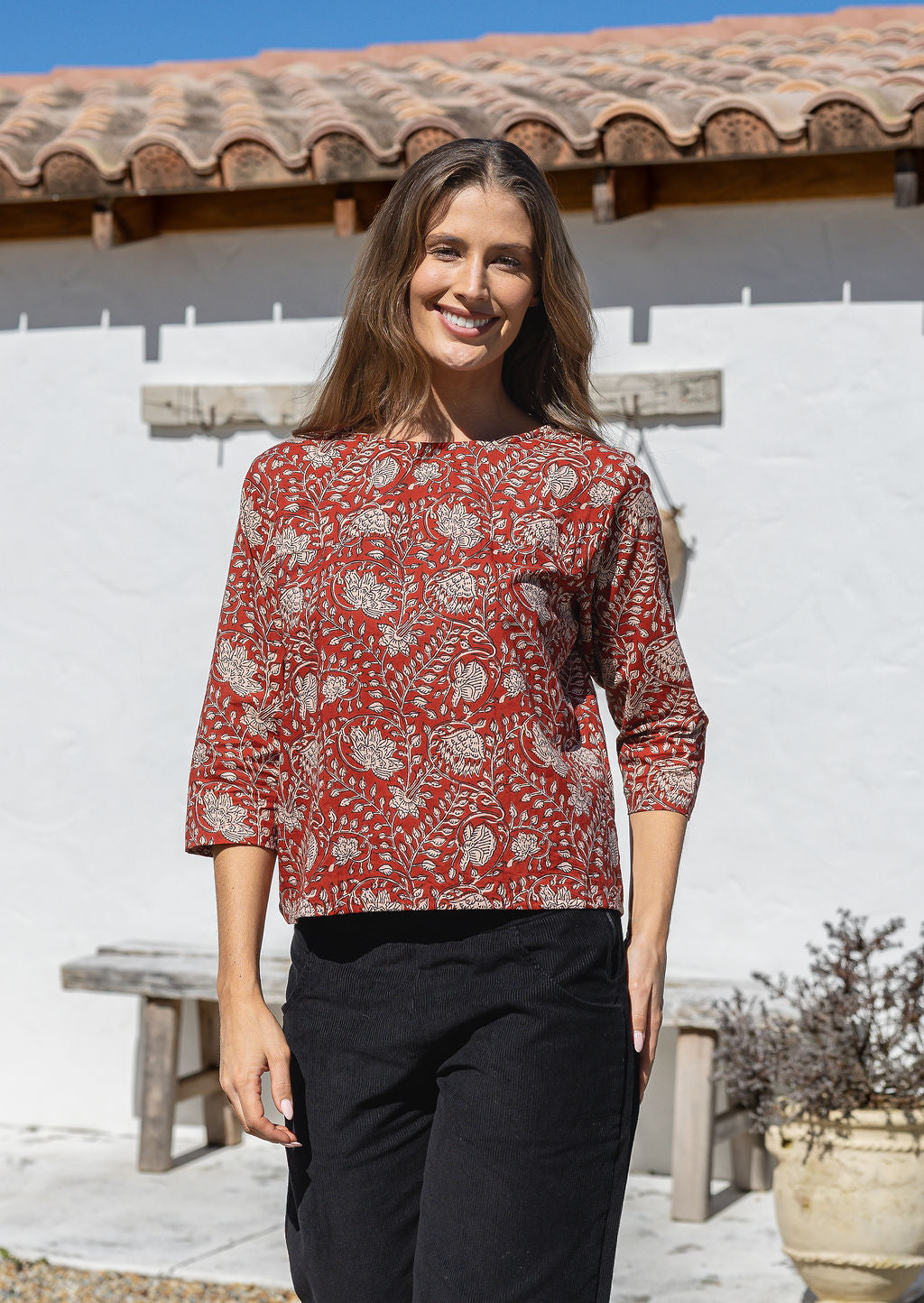 Model wears loose fit cotton top in red based floral print with black pants