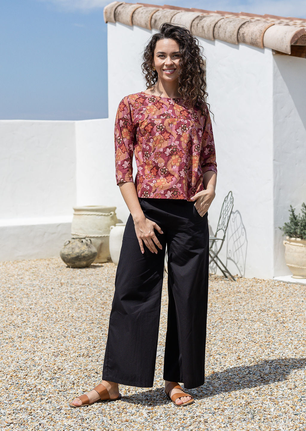 Model wears loose fit cotton top in warm toned Japanese style floral print with black pants