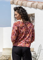 Woman stands showing the back of the cotton top with decorative buttons down the centre of the back.