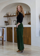Woman stands sideways wearing a cotton corduroy wide leg pants in olive green with a side zip.