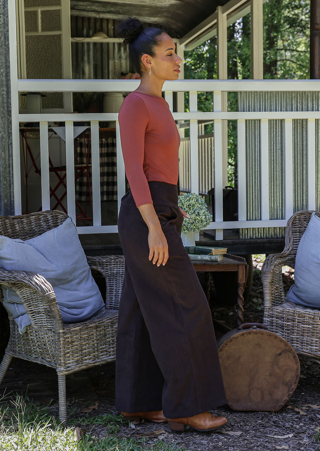 woman standing sideways wearing cotton corduroy pants in brown and basic top 