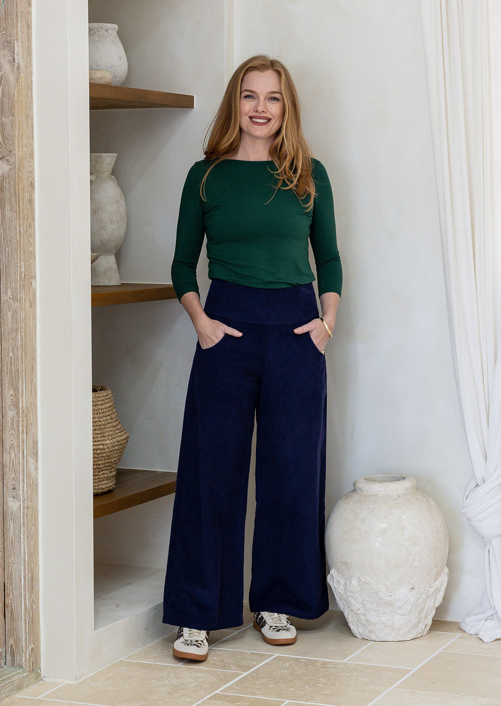 Woman wearing a corduroy wide leg pants in deep navy blue with both hand in pockets 