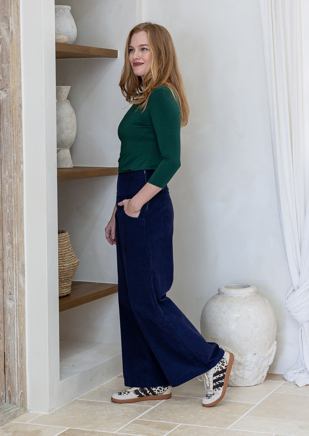 Woman standing sideways wearing a 100% cotton corduroy wide leg pants paired with green basic top