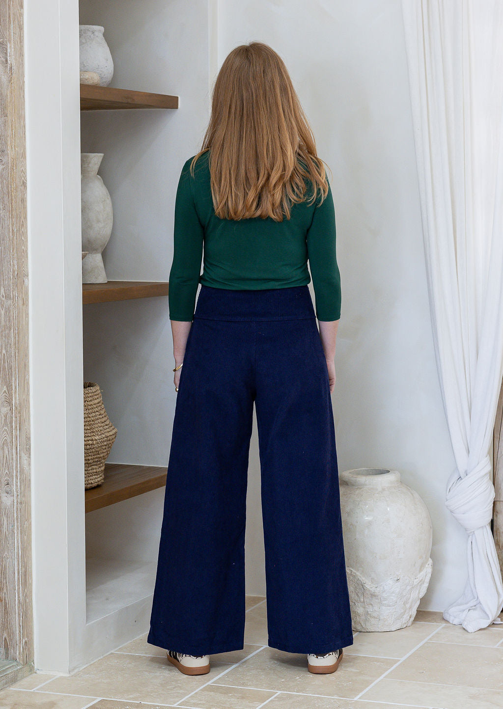 woman standing backwards wearing a 100% cotton corduroy wide leg pants paired with green basic top