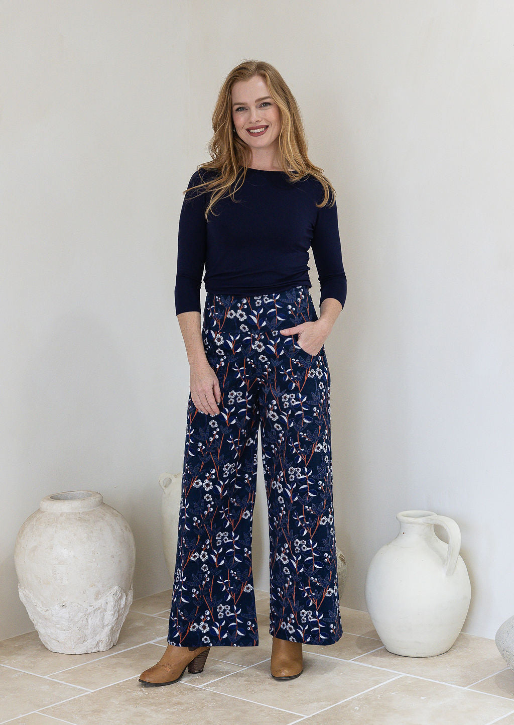 Woman wearing a wide leg cotton corduroy pants in navy blue based floral print paired with a basic top