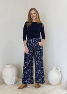 Woman wearing a wide leg cotton corduroy pants in navy blue based floral print paired with a basic top