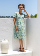 Model wearing a cotton knee length dress with empire waist, short sleeves and pockets.