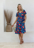 Model wearing a cotton V-neck short sleeve dress in royal blue based floral print 