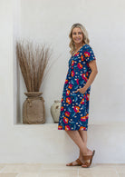 Model stands sideways wearing a cotton V-neck relaxed fit dress with empire waistline and short sleeves.