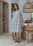 Model wearing a pure cotton V-neck short sleeve dress with empire waistline and  pocket in a dining room