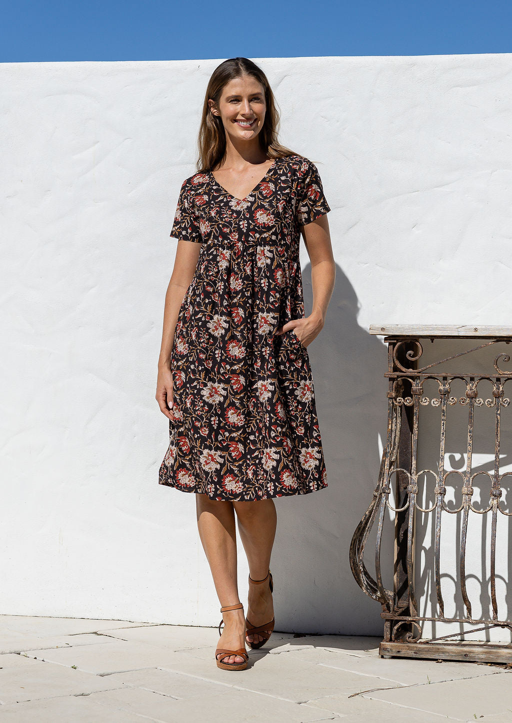 Model wearing a cotton V-neck short sleeve dress with empire waistline and  pocket.
