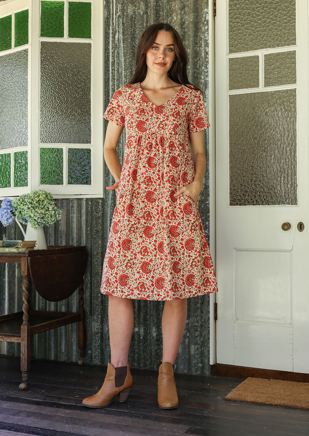 Model wearing a cotton V-neck short sleeve dress with empire waistline and  pocket.