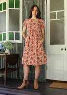 Model wearing a cotton V-neck short sleeve dress with empire waistline and  pocket.