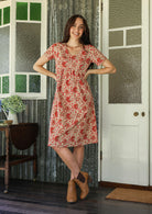 Model wearing a cotton V-neck relaxed fit dress with empire waistline and short sleeves.