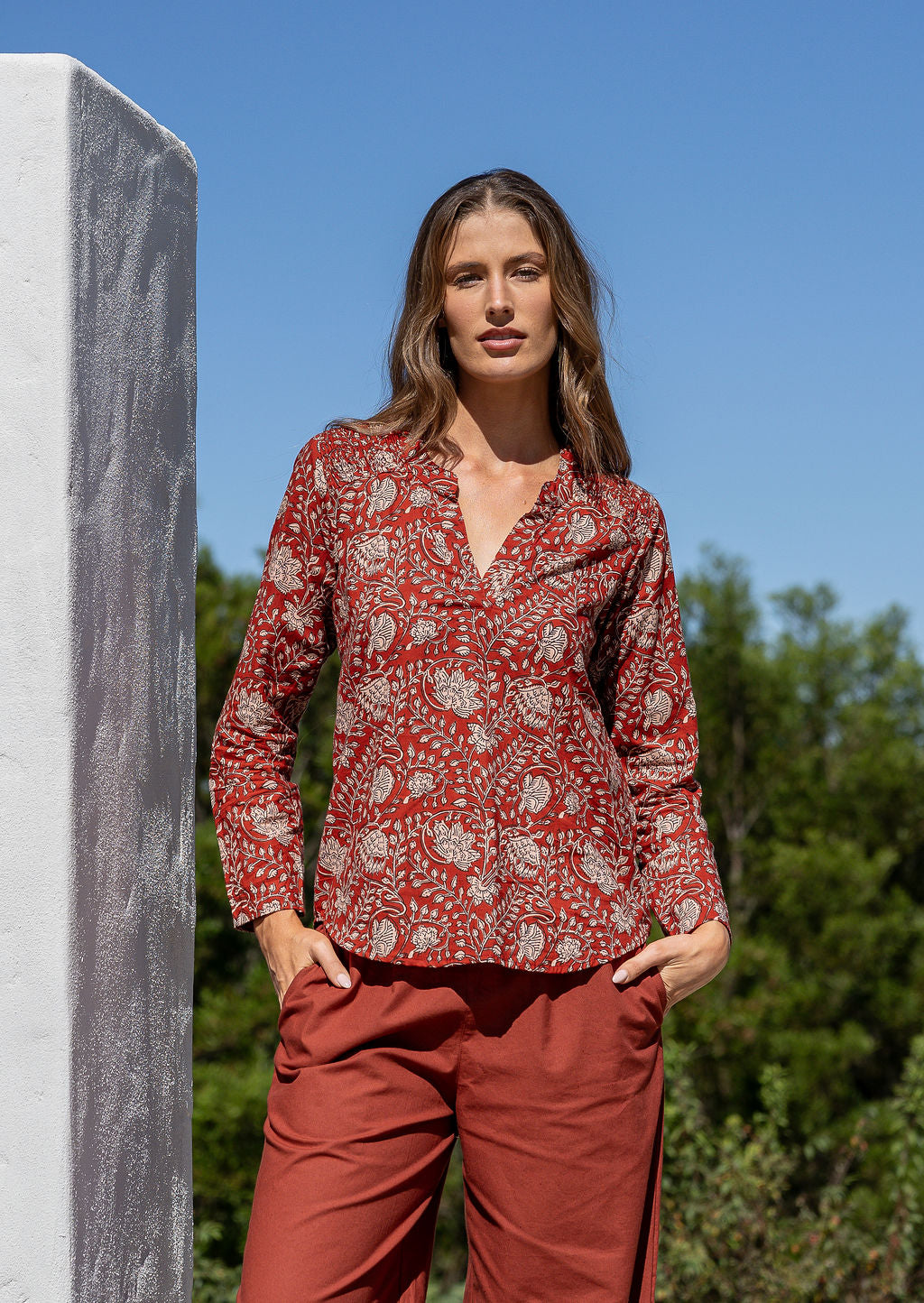 Woman wearing a 100% cotton top in red based floral print with V neckline
