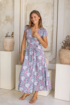 Woman wearing a floral dress standing in an interior setting with decorative elements.