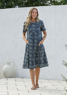 Woman wearing a navy blue based floral print cotton dress with hands in pocket