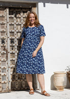 Woman poses in a navy based cotton floral short sleeve dress with round neckline