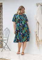 Woman wearing a 100% cotton lightweight lined relaxed fit knee length dress with pin tucks and pockets 