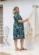 Woman stands sideways wearing a 100% cotton lightweight lined relaxed fit knee length dress 