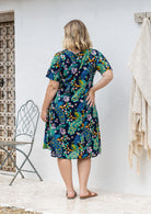 Woman stands backwards wearing a 100% cotton lightweight lined relaxed fit knee length dress.
