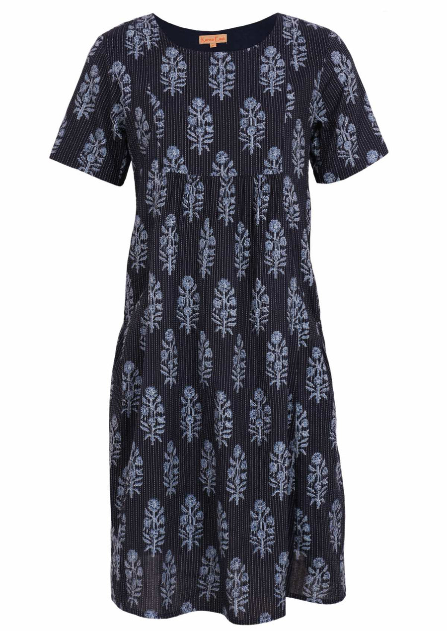 Woman standing in front of church door with navy blue cotton Indian print summer dress with hand in pocket