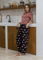 Woman wearing a pink top and dark floral print wide leg cotton pants with pleated ankles, elastic waist and pockets