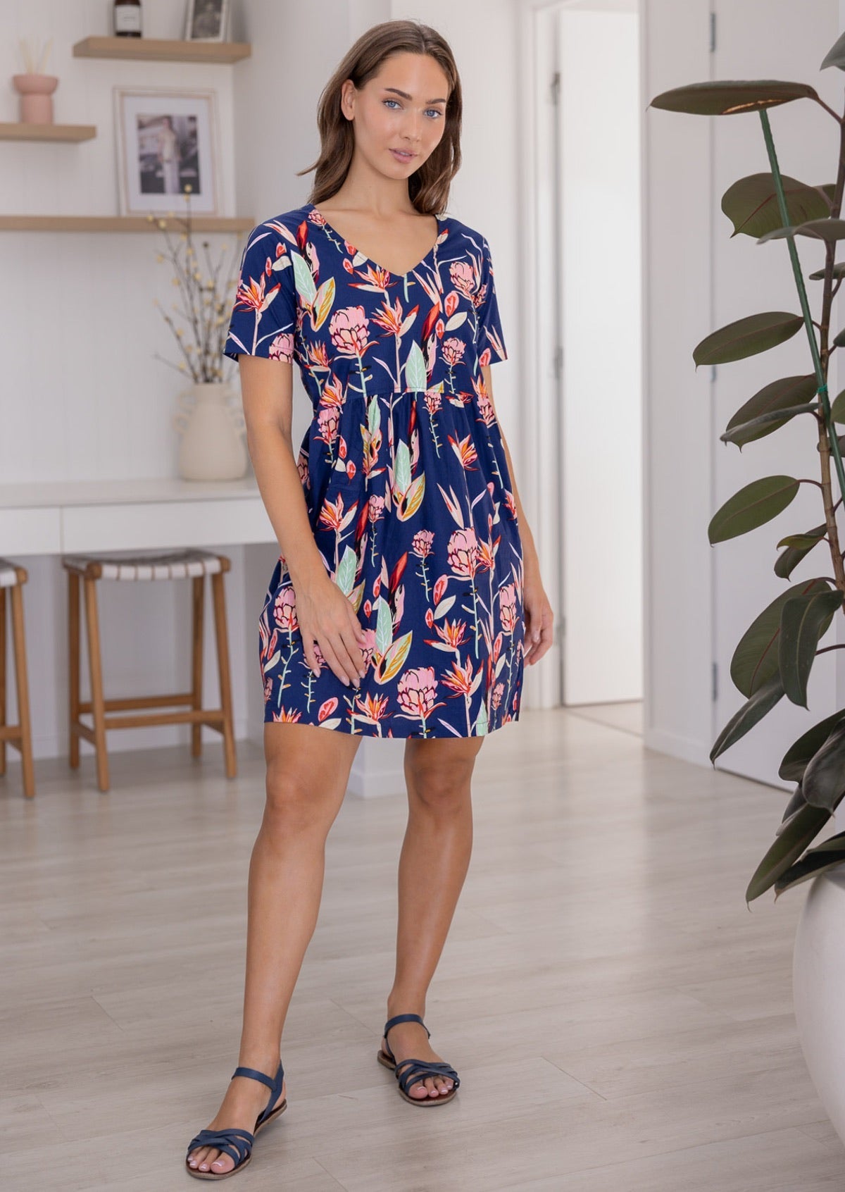 Woman wearing a 100% cotton bold botanic printed dress with V-neckline and pockets