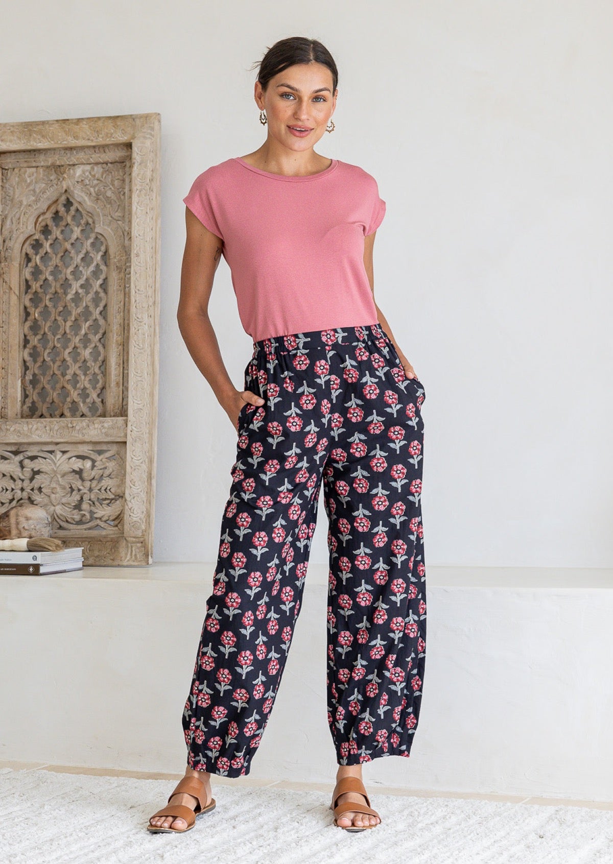 Woman wearing a 100% cotton black floral print wide-leg pants paired with a pink top. 