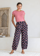 Woman wearing a 100% cotton black floral print wide-leg pants paired with a pink top. 