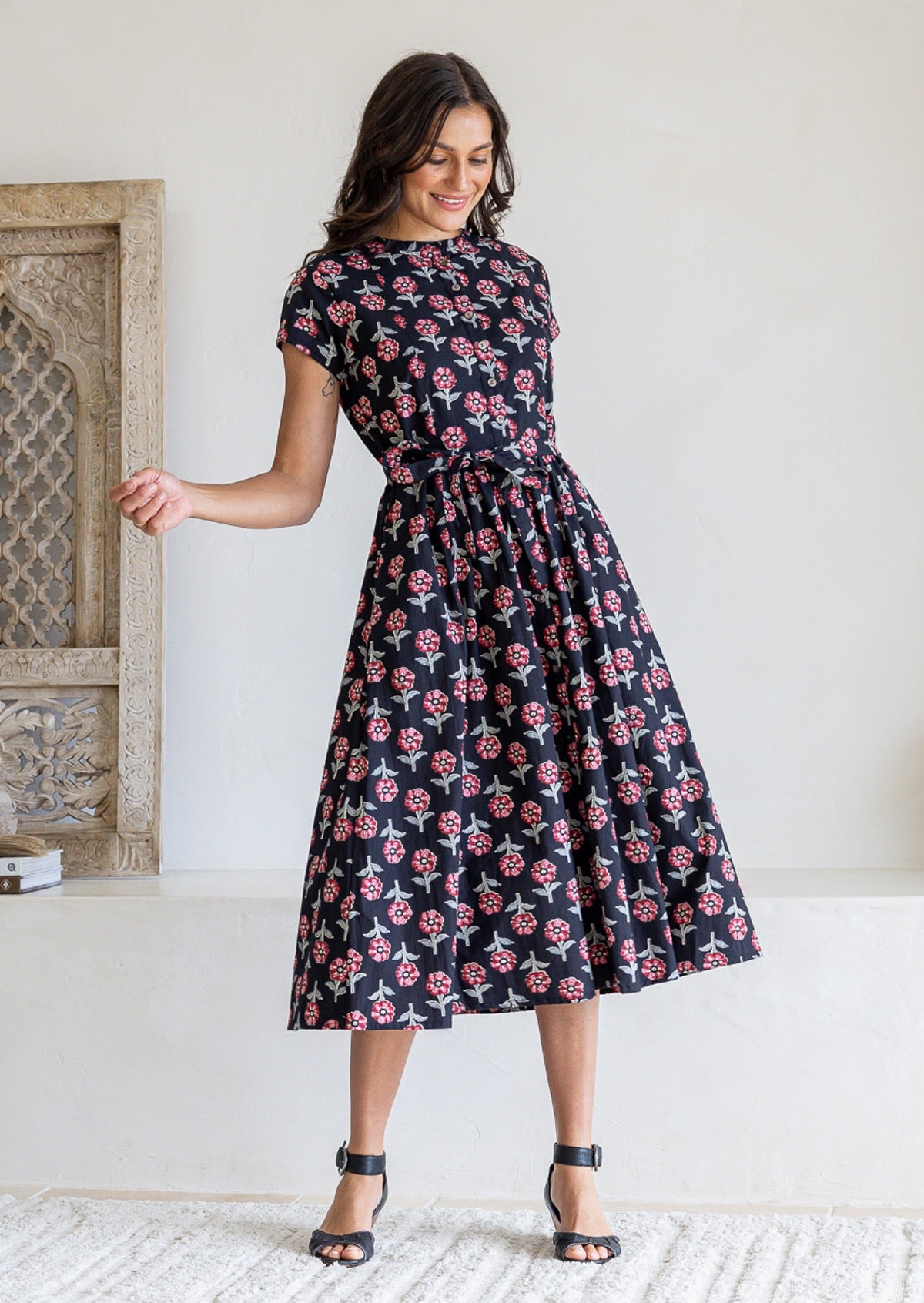 Woman wearing a 100% cotton black floral print midi dress with short sleeves and gathered skirt. 