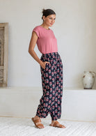 Model stands sideways wearing a 100% cotton printed wide leg cotton pants featuring pleated ankles and pockets.