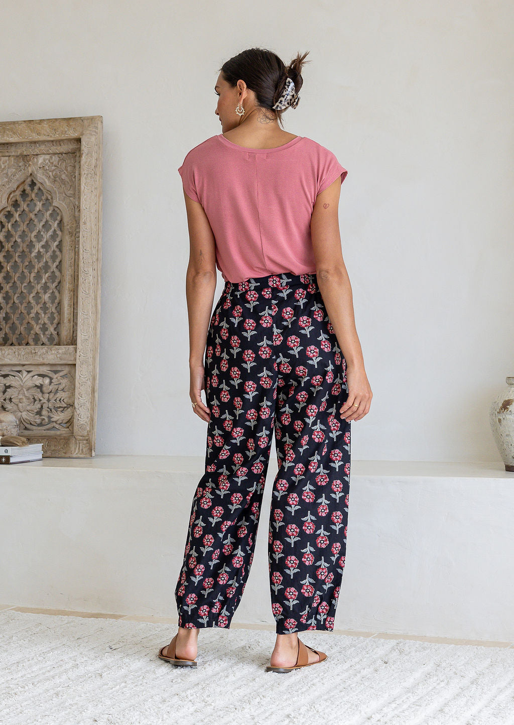 Model stands backwards wearing a 100% cotton printed wide leg cotton pants featuring pleated ankles and pockets.
