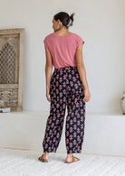 Model stands backwards wearing a 100% cotton printed wide leg cotton pants featuring pleated ankles and pockets.