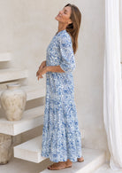 Model posing slight sideways in 3/4 sleeved long maxi dress with buttoned bodice and pockets.