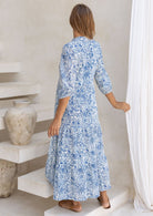 Model in 3/4 sleeves, relaxed fit tiered maxi dress in white based blue floral print.
